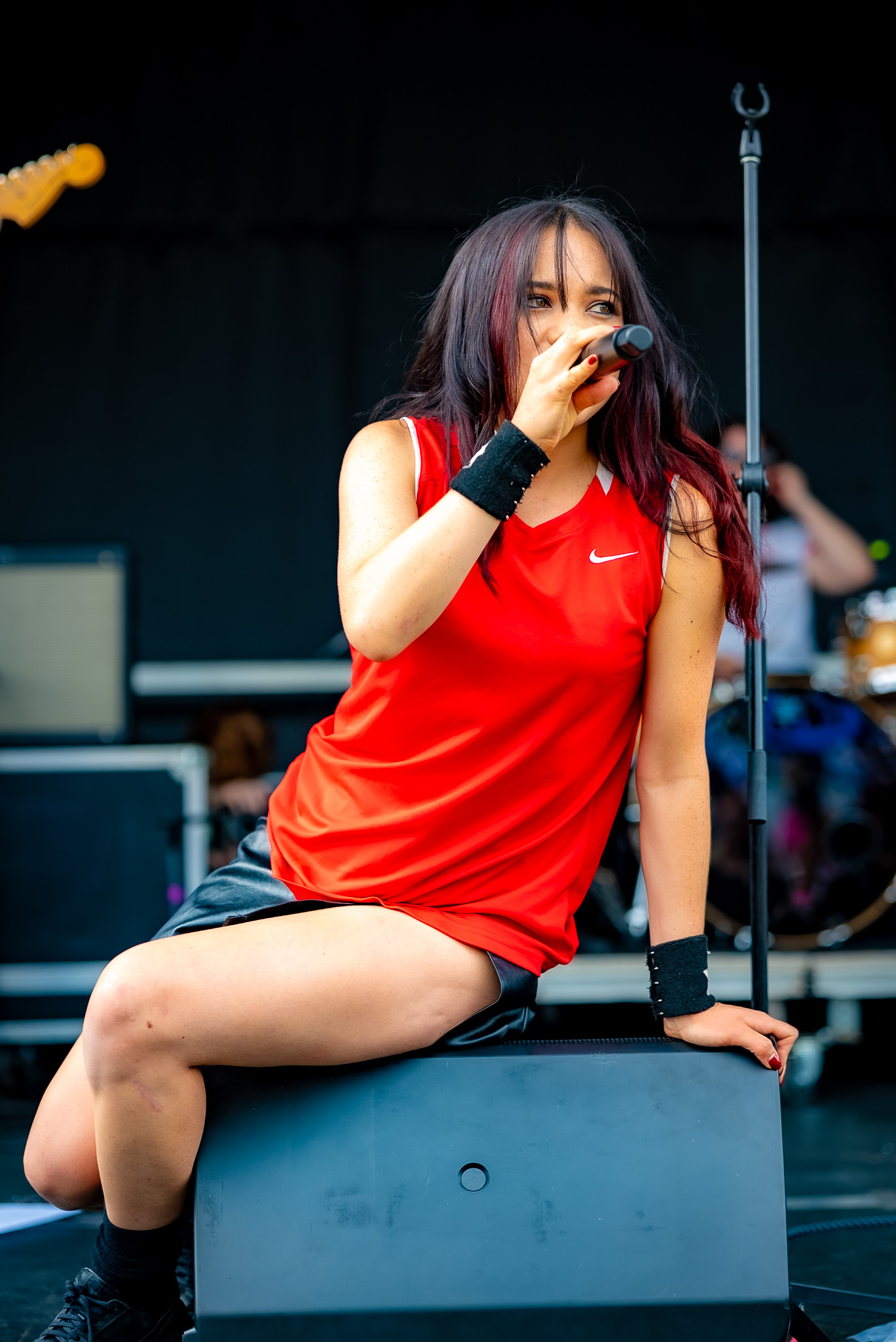Singer seated on a stage monitor during a local set