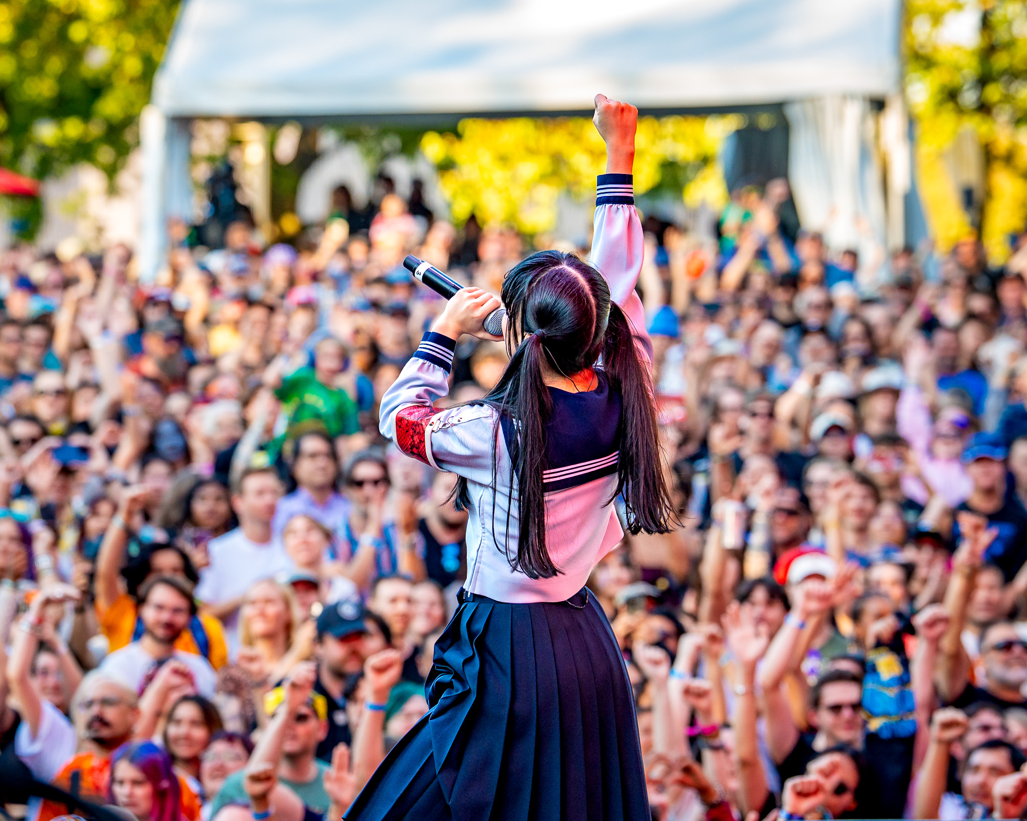 ATARASHII GAKKO! raising a fist toward a packed Bumbershoot crowd